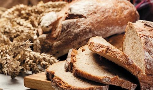 WHOLE GRAINS AND BREAD ON CUTTING BOARD